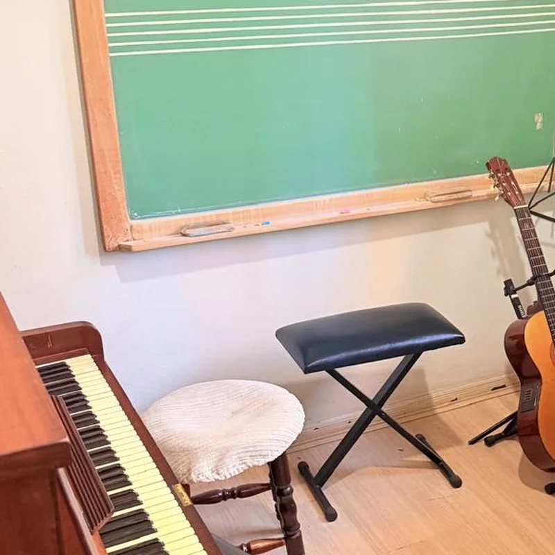 Sala de aula do Studio Musical com piano acústico e lousa pautada